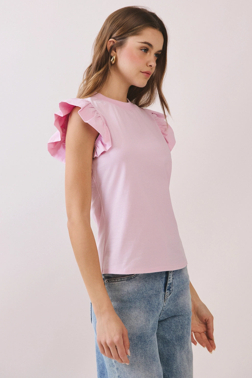 Woman wearing a pink top with ruffled sleeves on a plain background