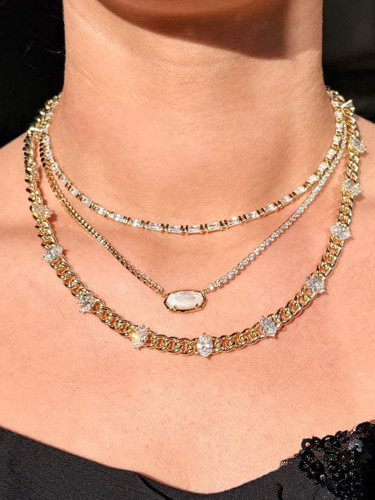 Close-up of a person wearing multiple gold necklaces with clear stones on a black background