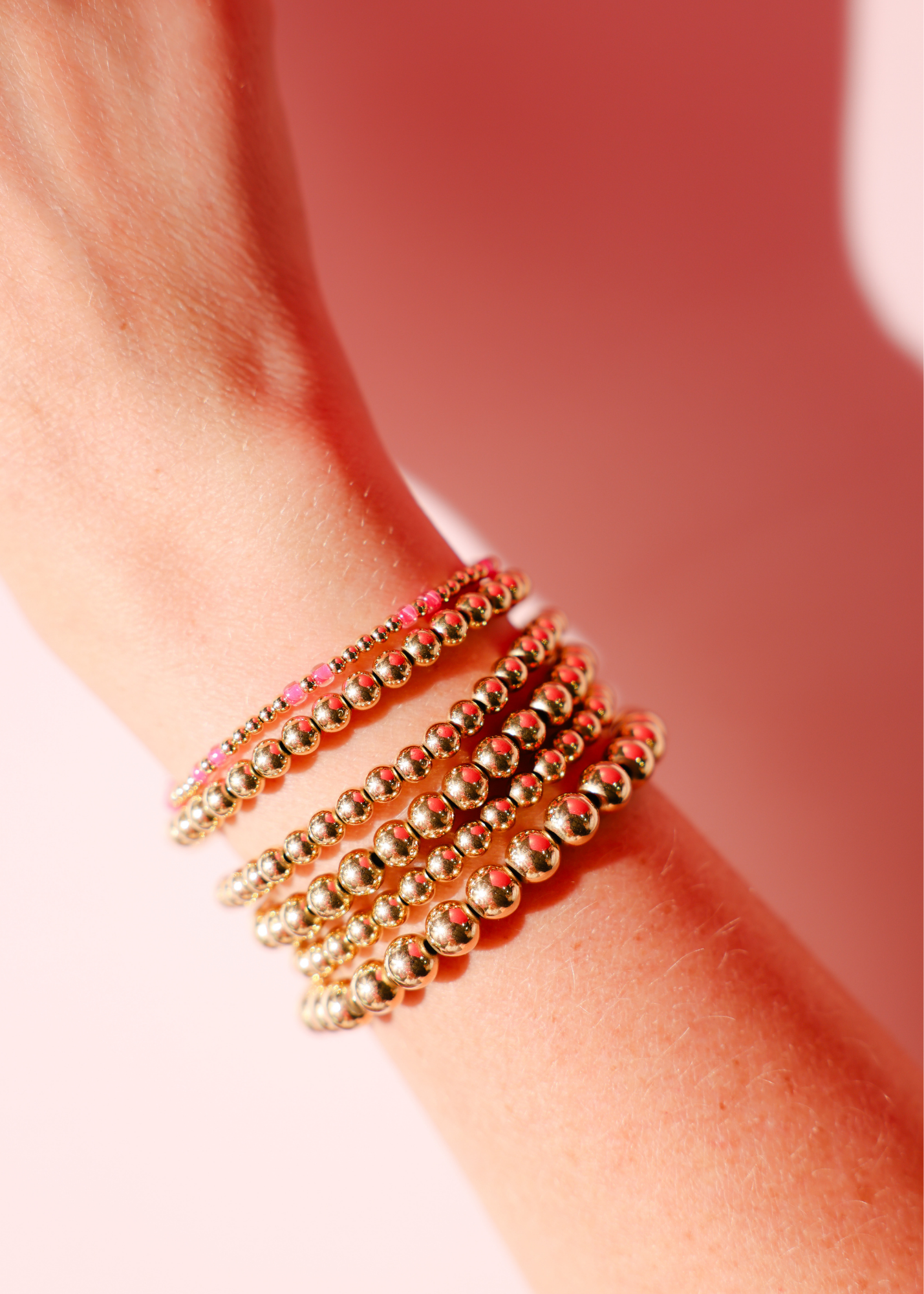 Gold beaded bracelets on a wrist with a blurred background
