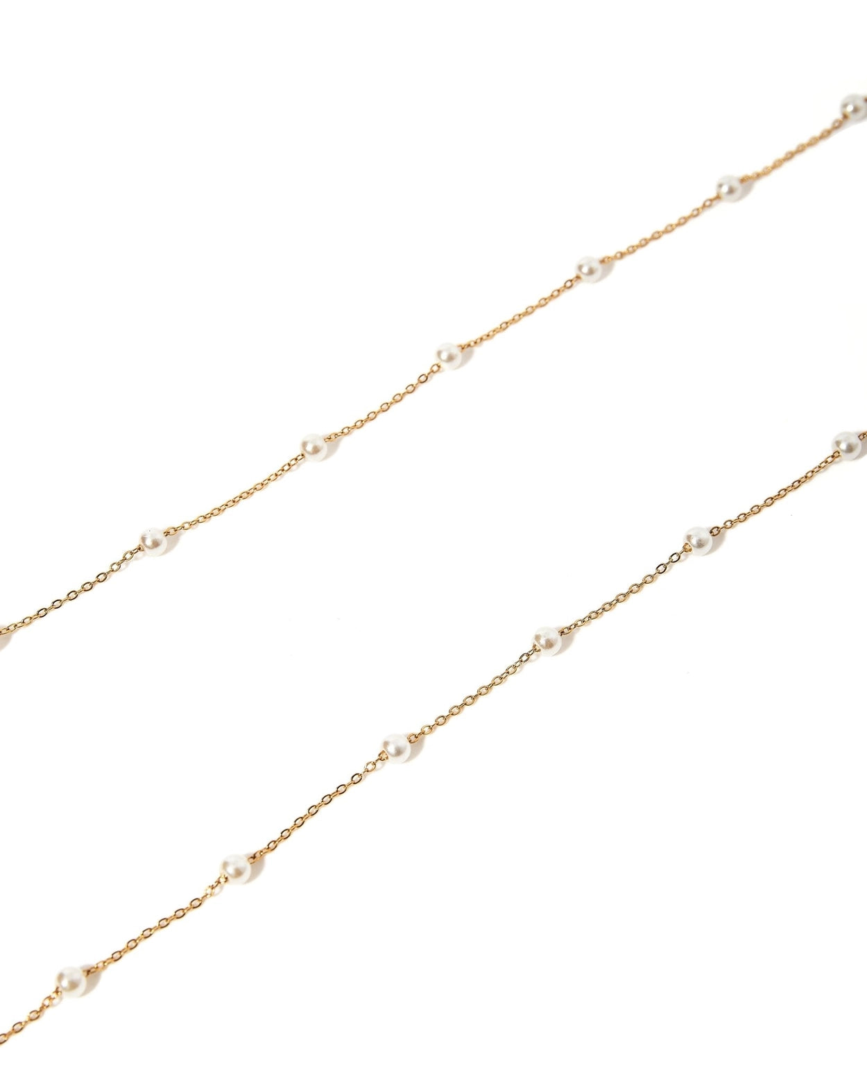 A delicate gold chain necklace featuring small, evenly spaced white pearl beads, displayed diagonally on a clean white background.