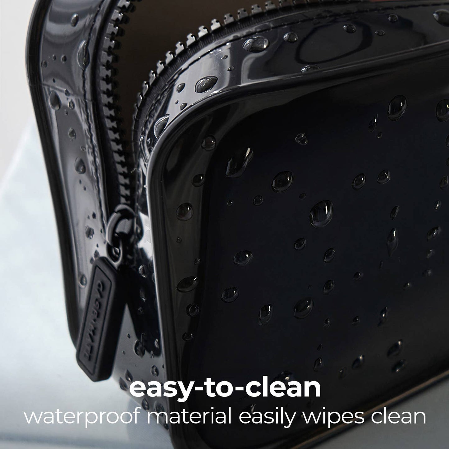Close-up of a glossy black waterproof zippered pouch with water droplets on the surface, featuring a zipper pull tab and text overlay that reads 'easy-to-clean waterproof material easily wipes clean'.