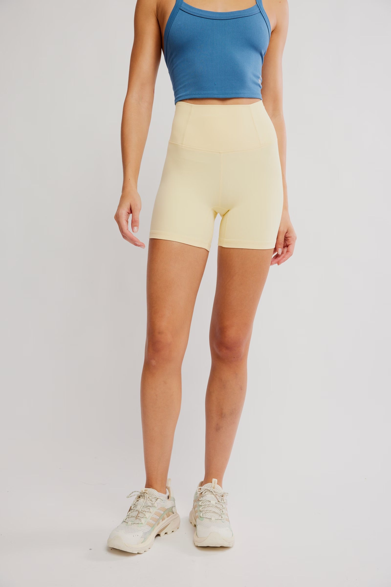 Person wearing a blue sports bra and yellow shorts on a plain background