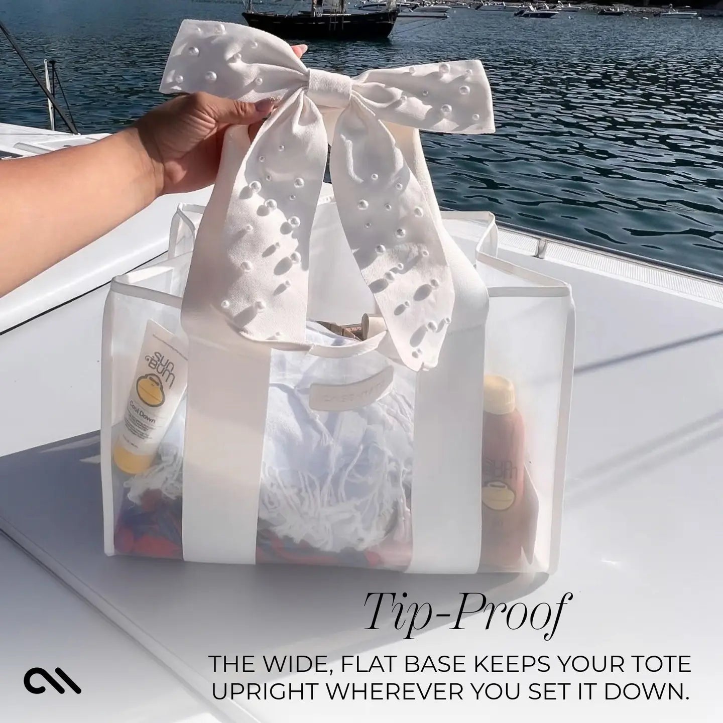 Clear tote bag with a white bow held by a hand on a boat with water in the background