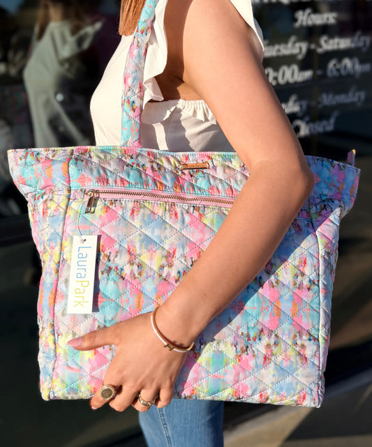 Person holding a colorful quilted bag with a visible brand label.