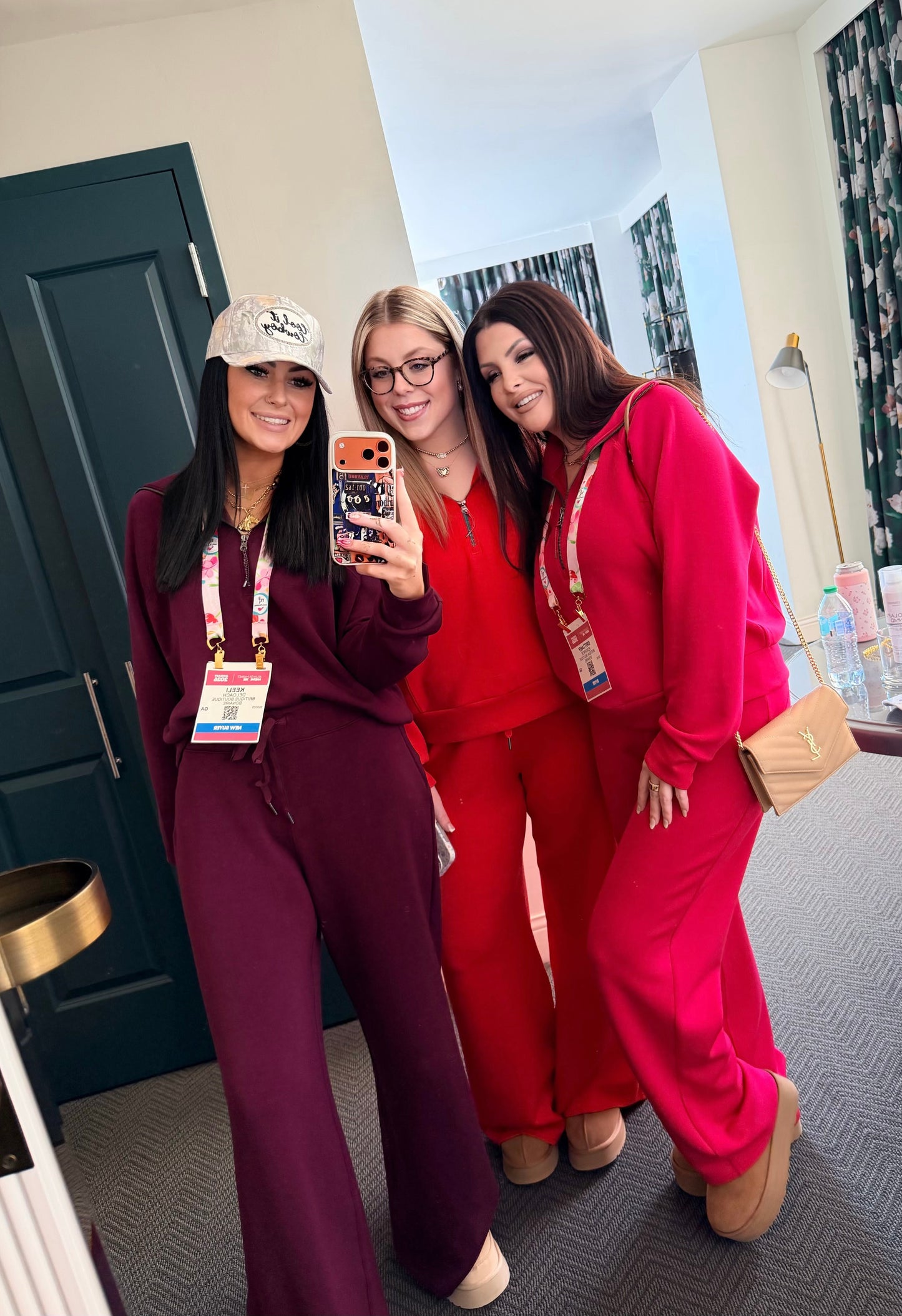 Three women in colorful outfits taking a selfie in a room with decor elements.