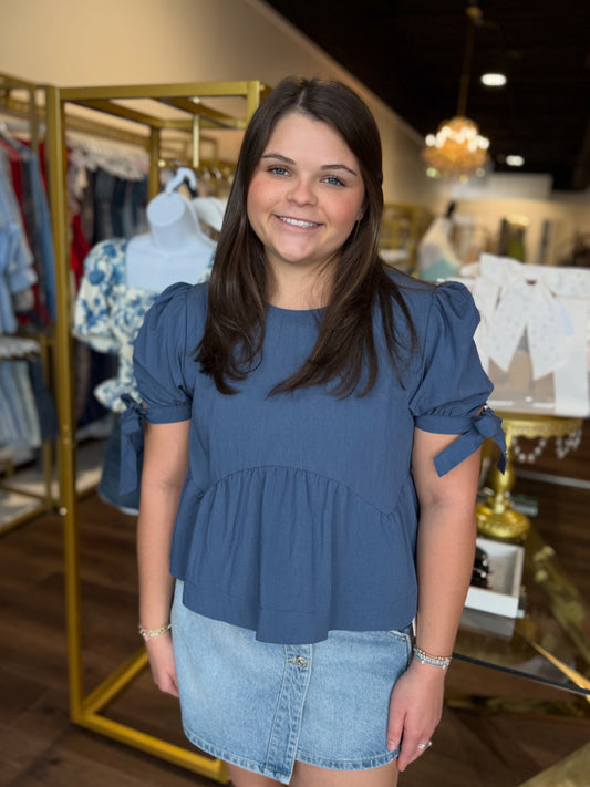 Woman wearing a blue top and denim skirt in a store setting