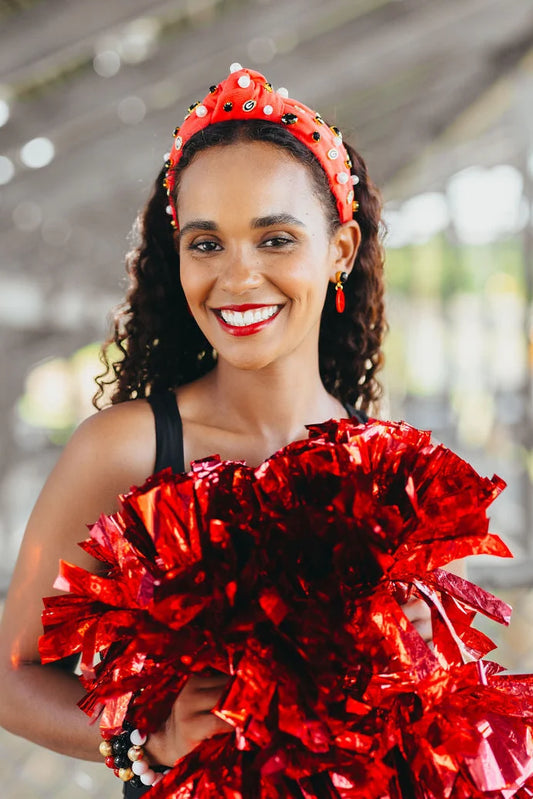 Woman in red cheerleading outfit with pom-poms and headband