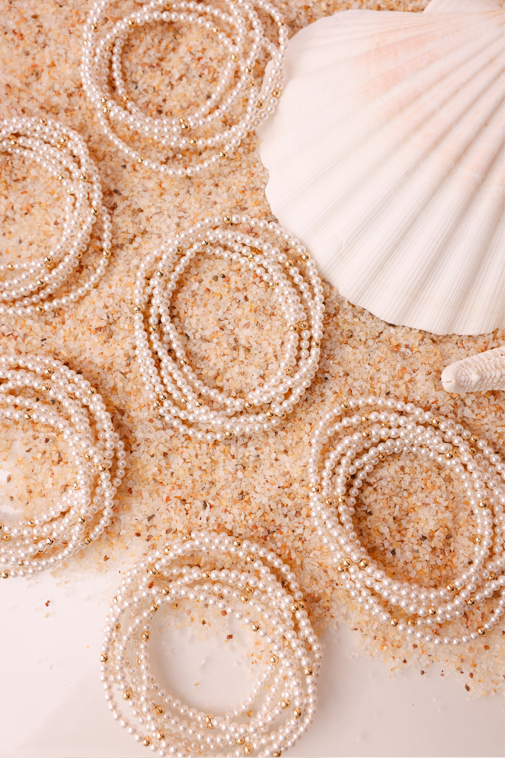 Pearl bracelets and a shell on sand