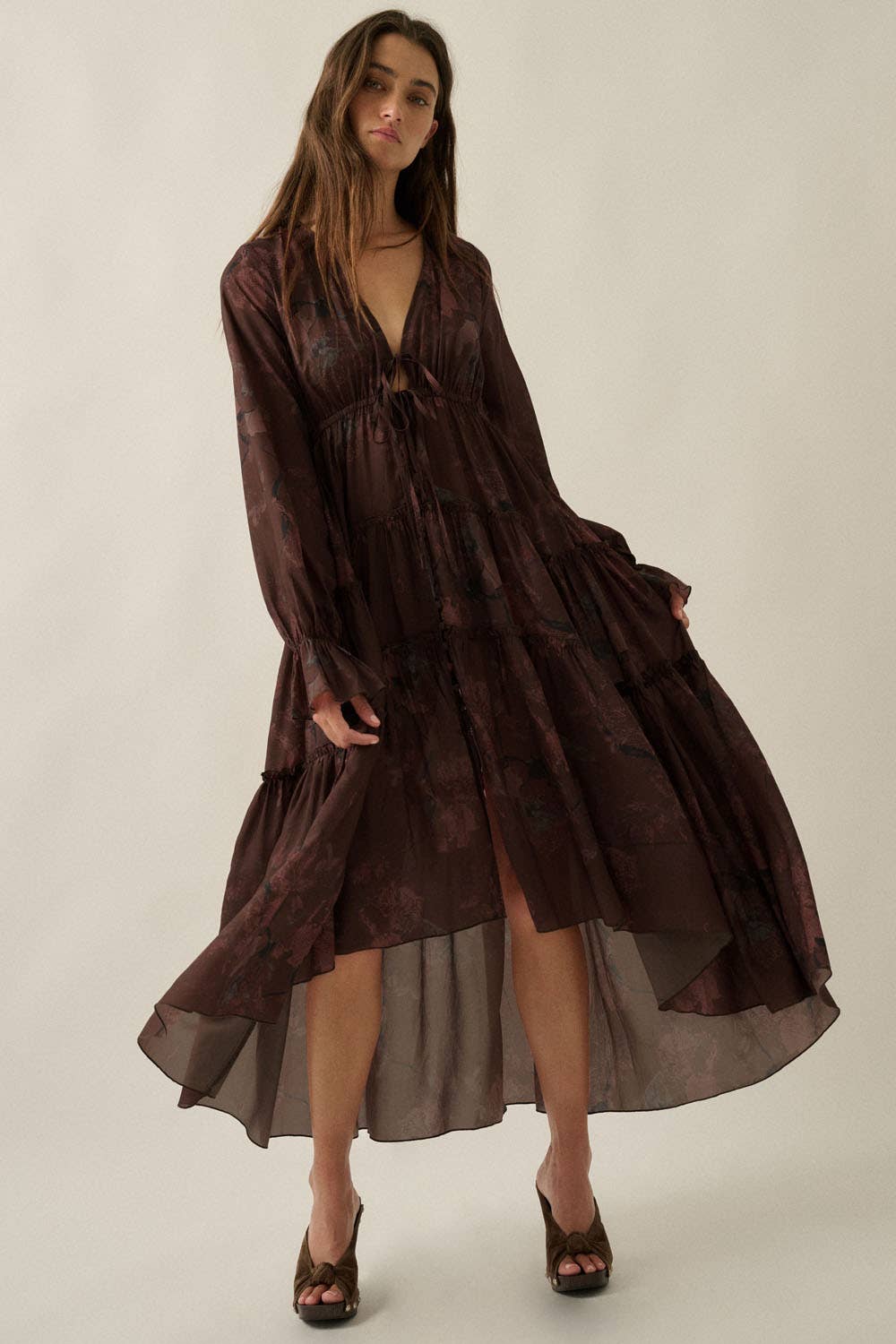 Woman wearing a long brown dress against a plain background