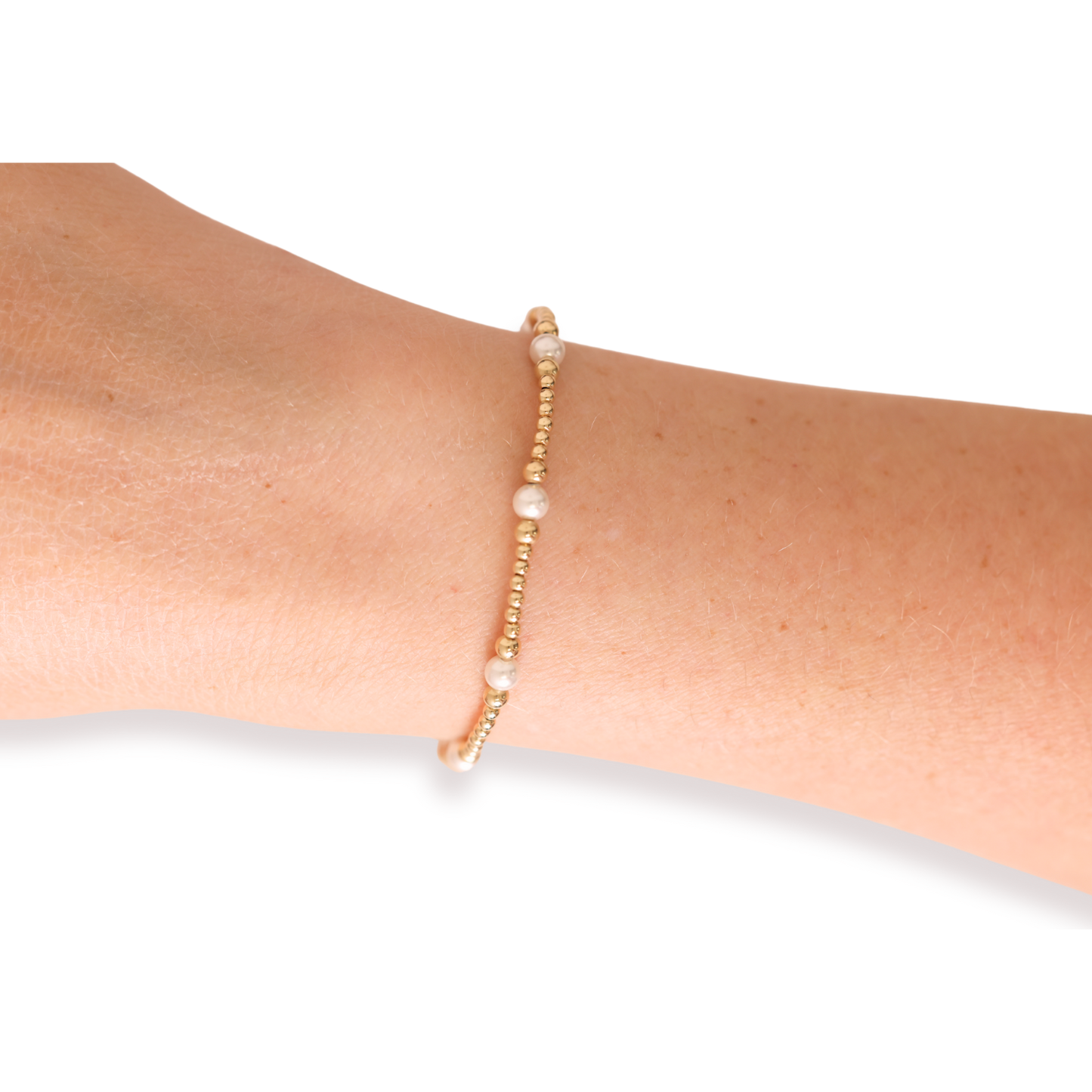 Gold bracelet with small beads on a wrist against a white background