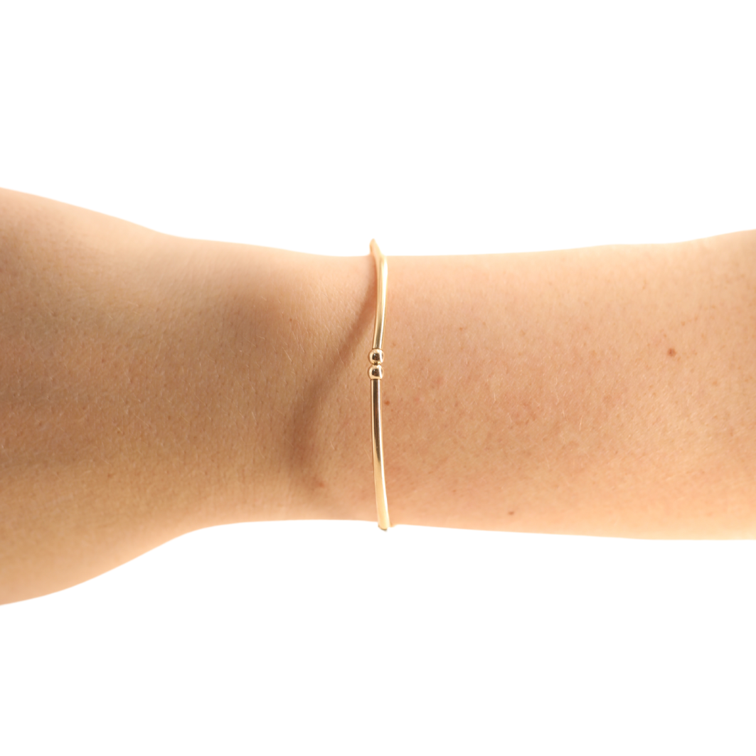 Gold bracelet on a person's wrist against a white background