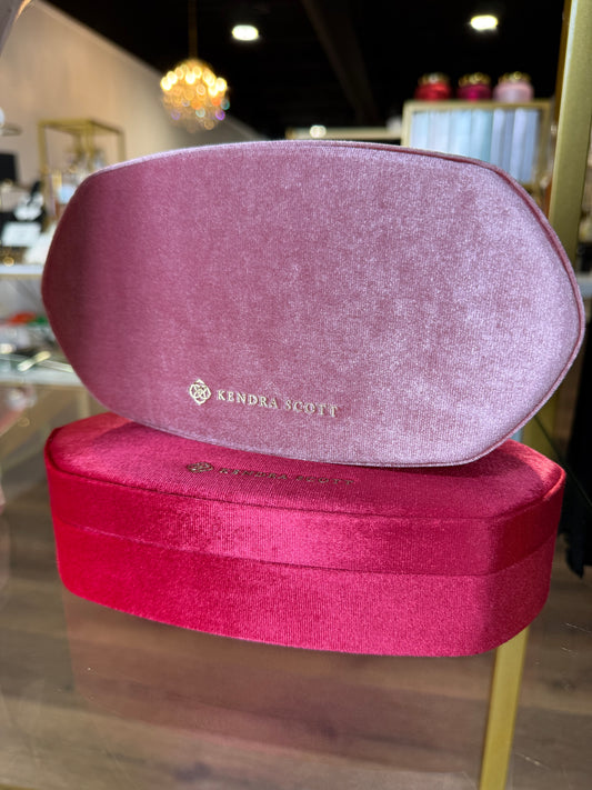 Two pink jewelry boxes with a brand logo on a blurred background