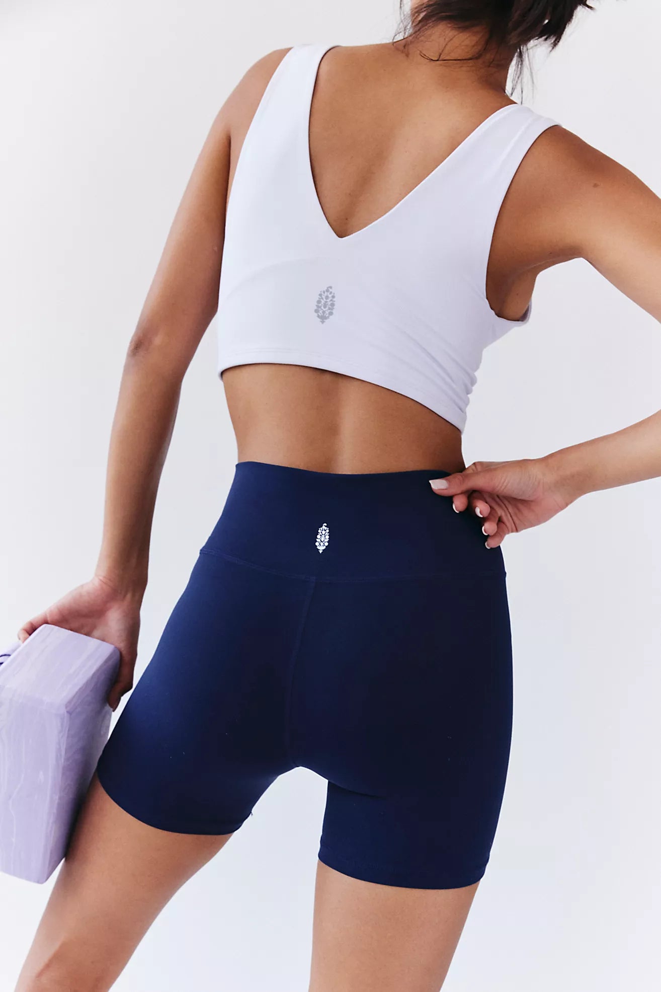 Person wearing a white sports bra and navy shorts on a plain background