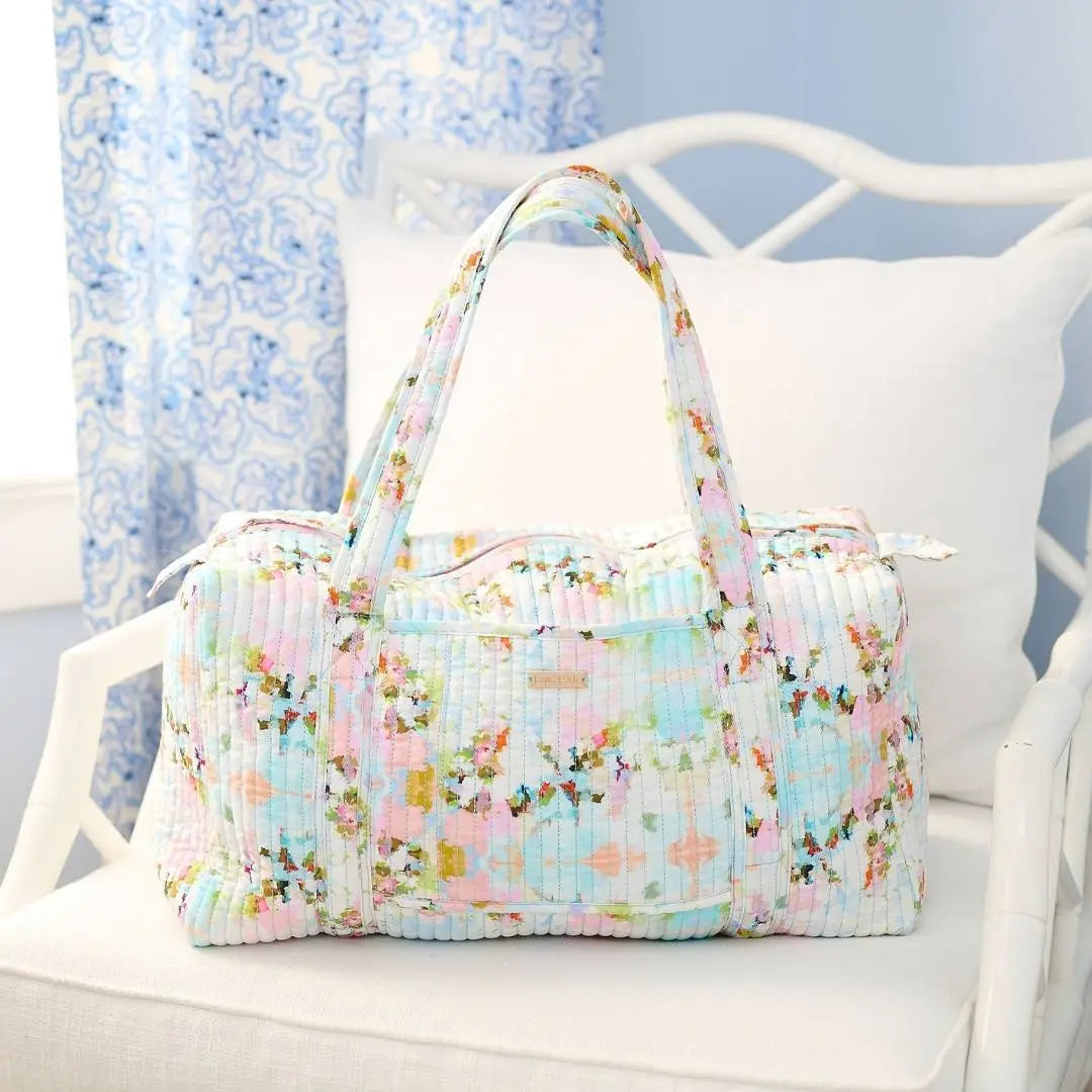 Floral patterned bag on a white chair with a light blue curtain background
