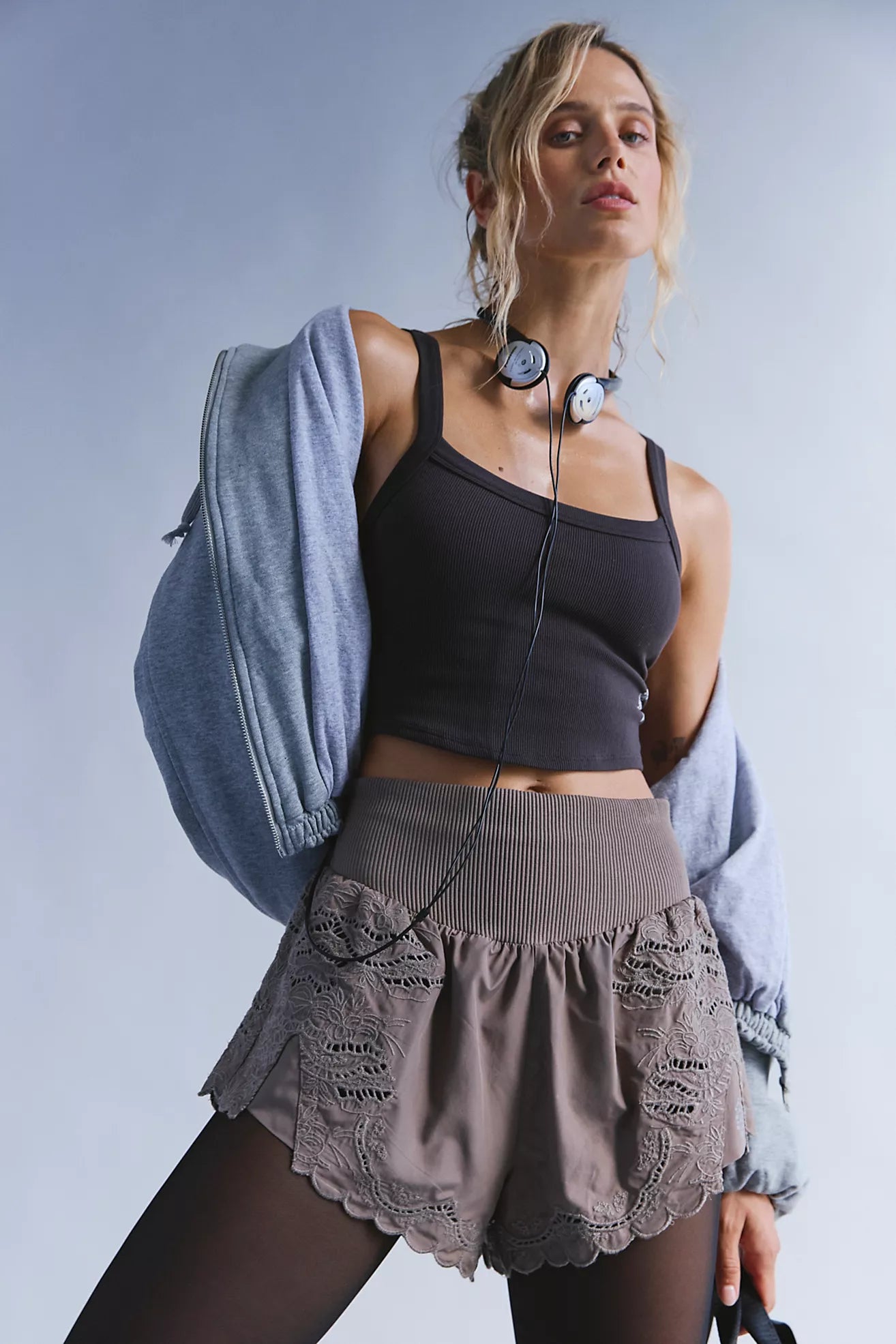 Woman in athletic wear with a light blue jacket on a plain background