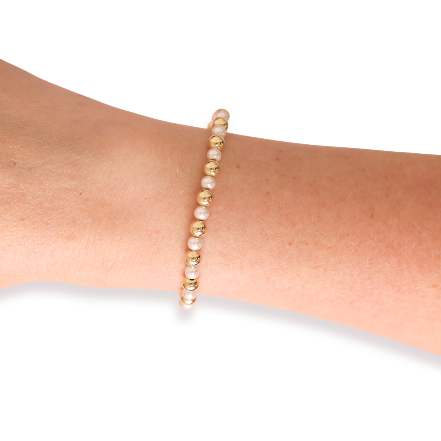 Pearl and gold beaded bracelet on a wrist against a white background