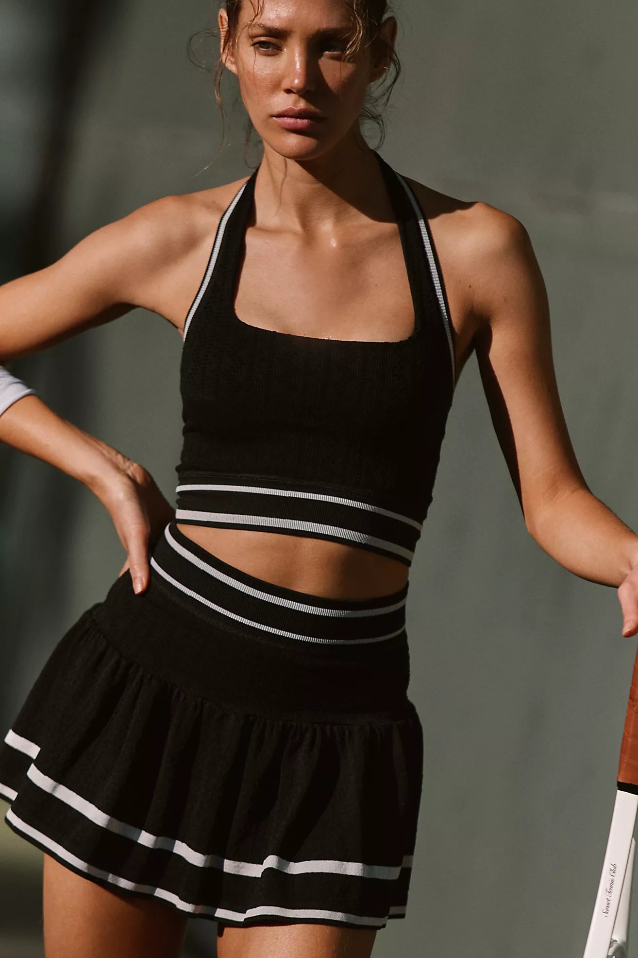 Woman wearing a black sports outfit with white stripes against a neutral background