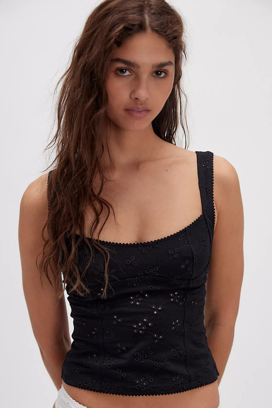 Woman wearing a black top and white underwear with a plain background