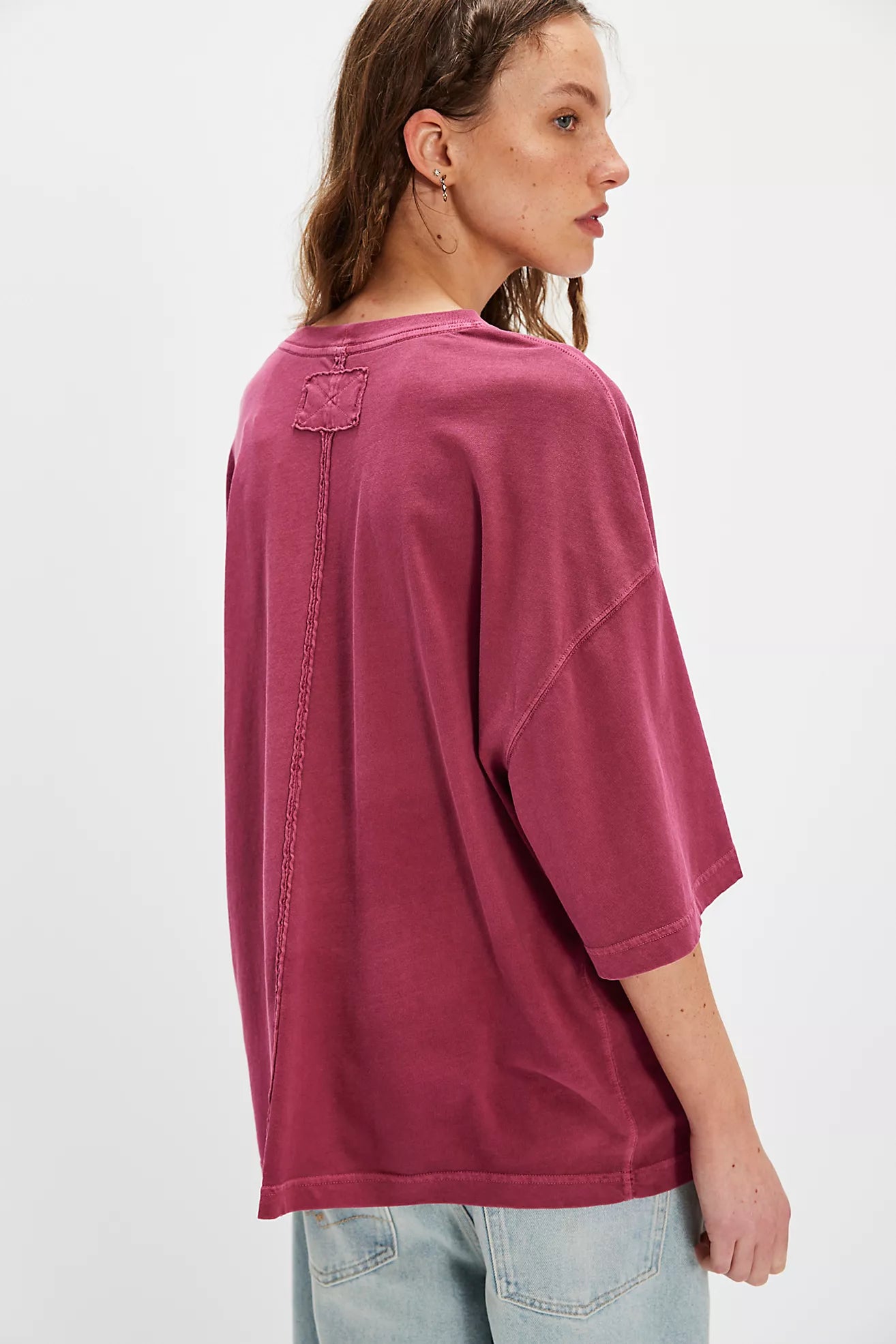 Person wearing a maroon oversized t-shirt on a white background