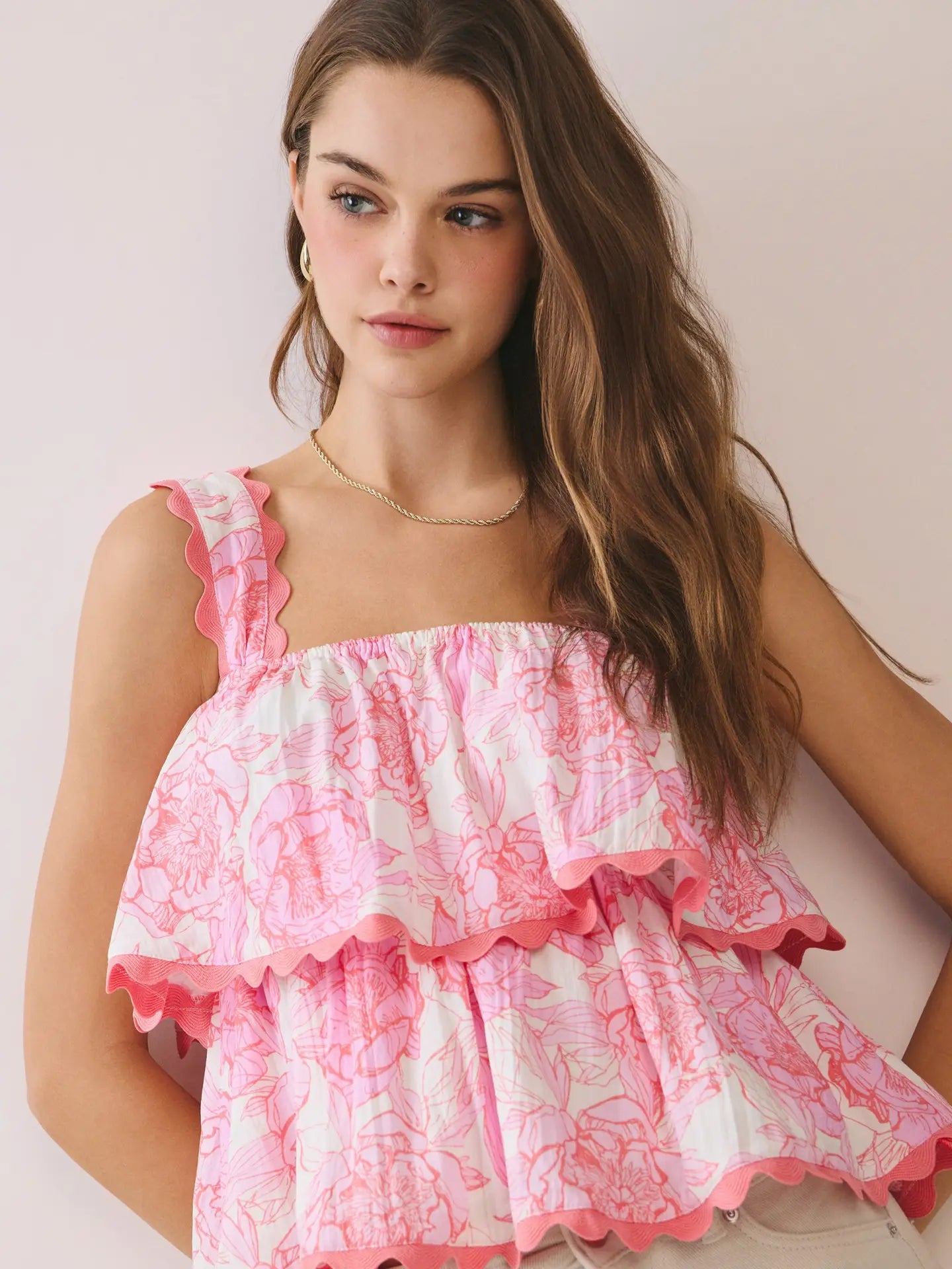 Woman wearing a pink floral dress against a plain background