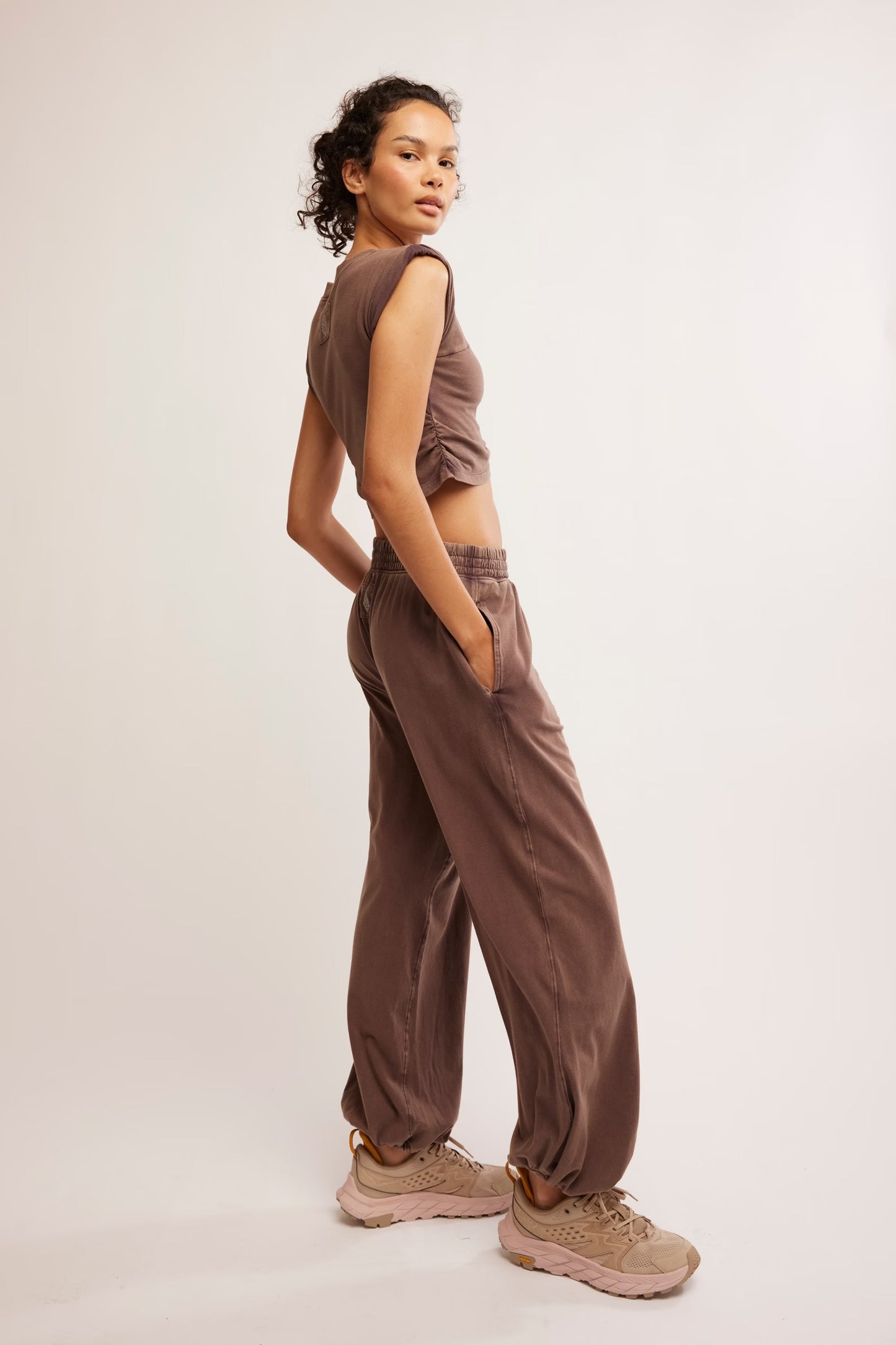 Woman wearing a brown sleeveless top and pants on a white background