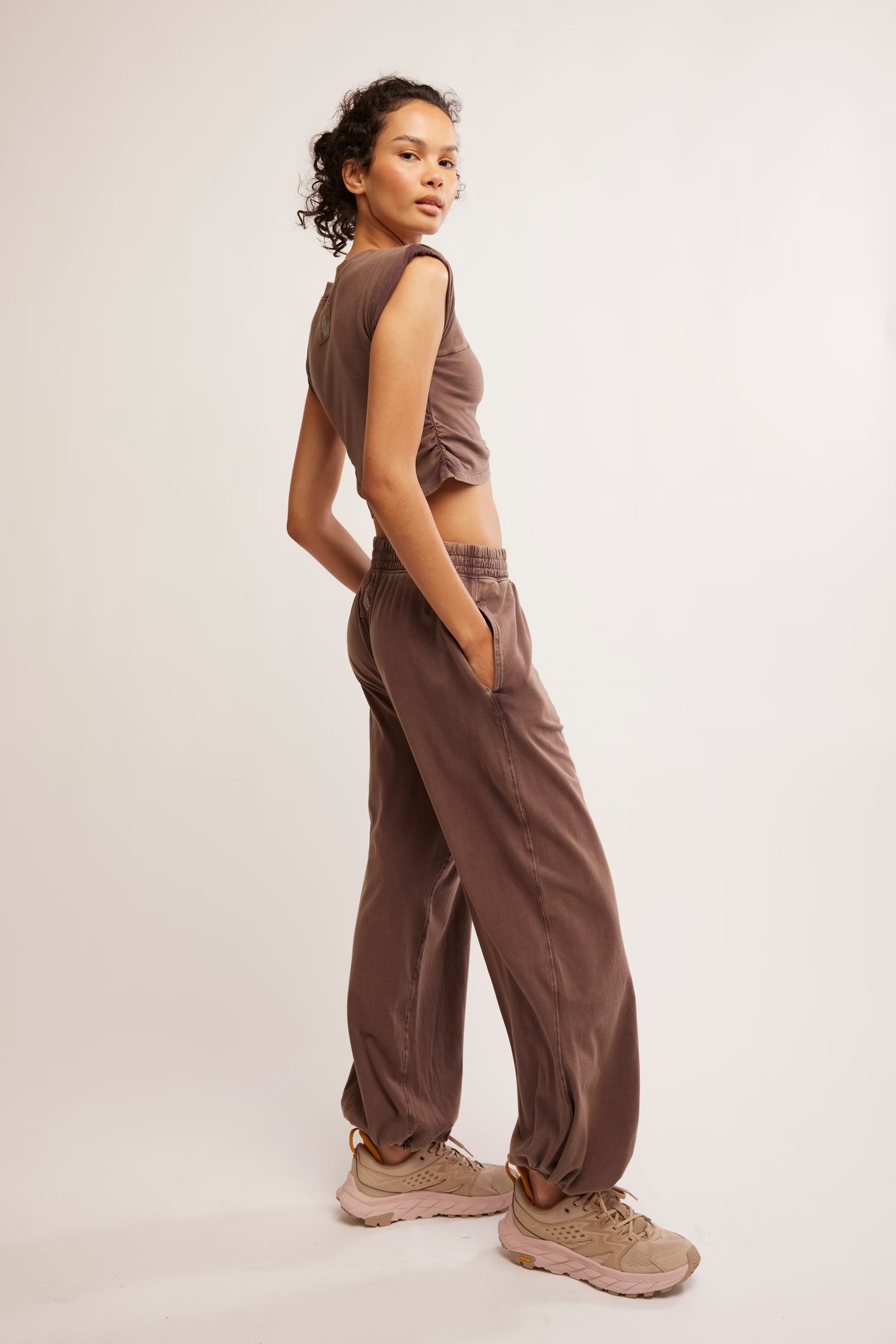 Woman wearing a brown sleeveless top and pants on a white background
