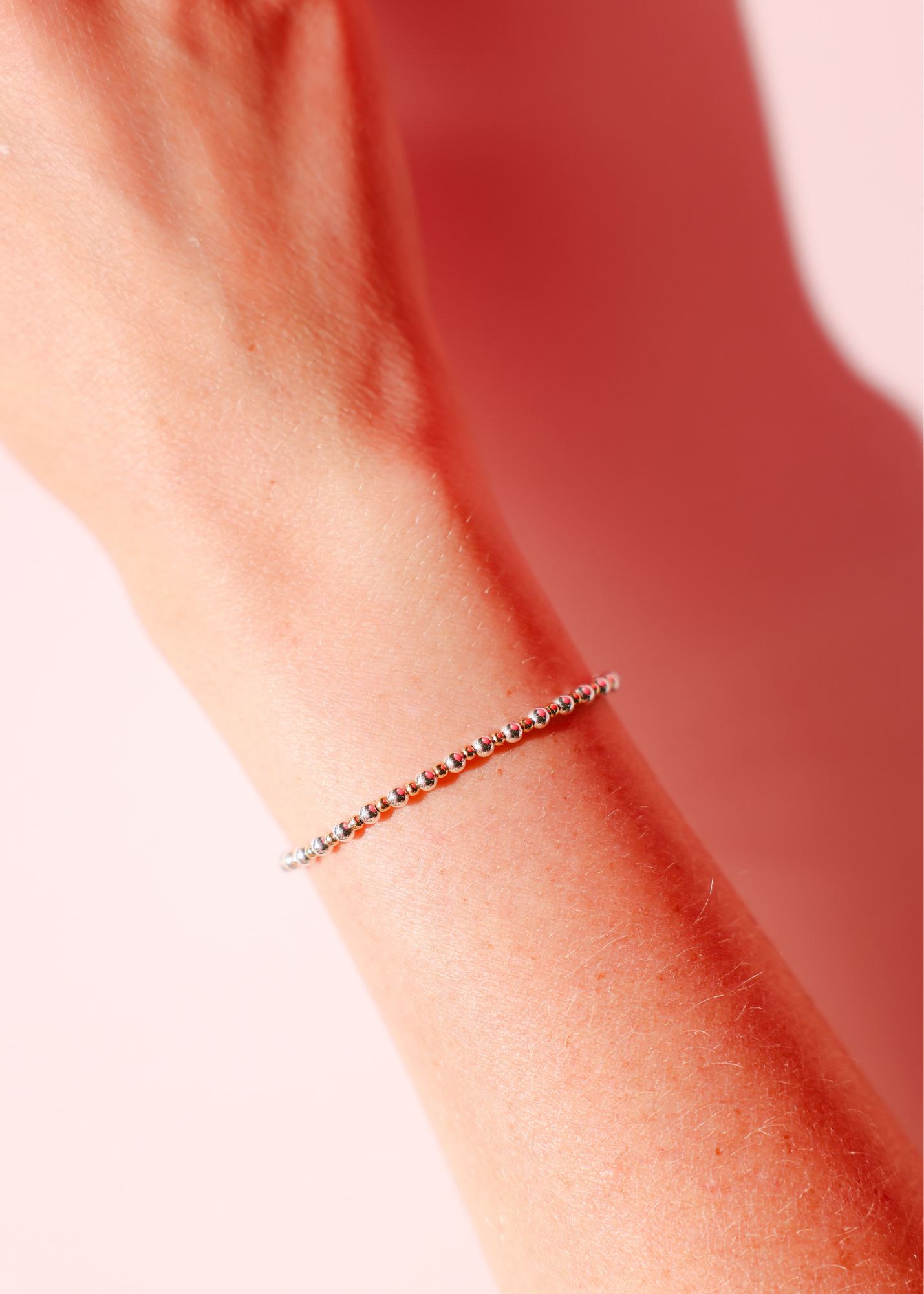 Close-up of a wrist wearing a thin bracelet on a blurred background