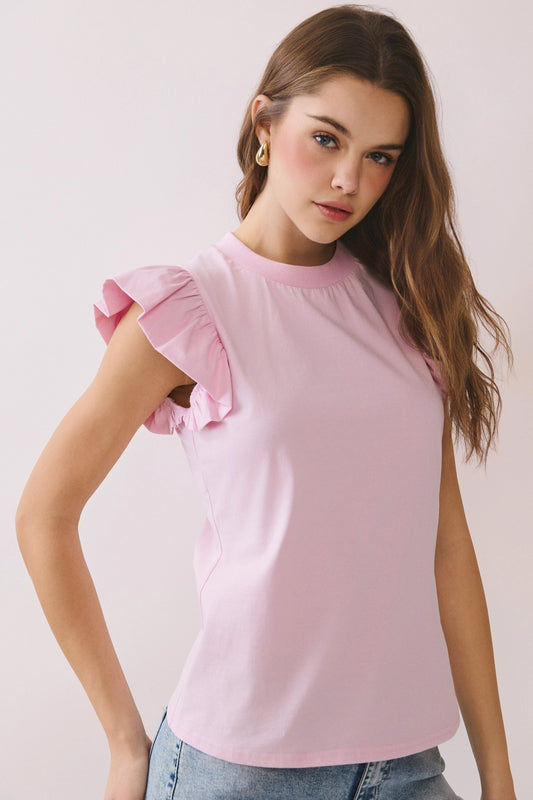 Woman wearing a pink blouse with ruffled sleeves against a plain background