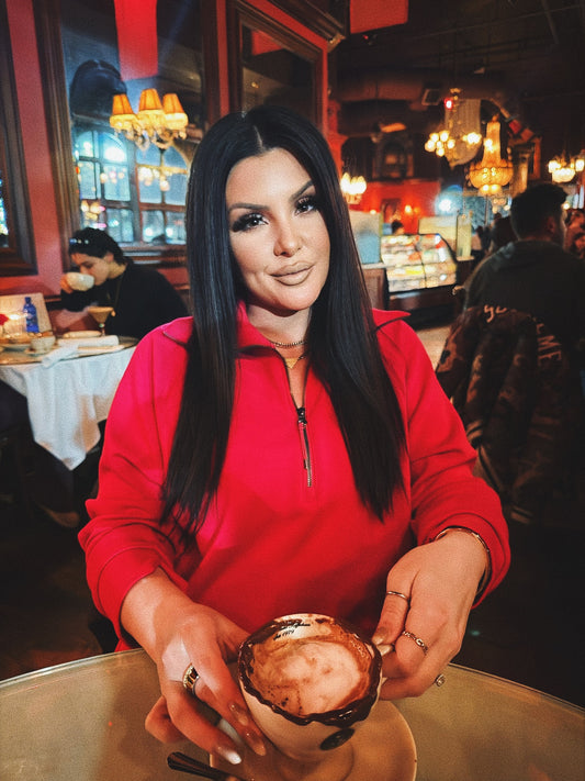 Woman in a red jacket holding a cup in a restaurant setting