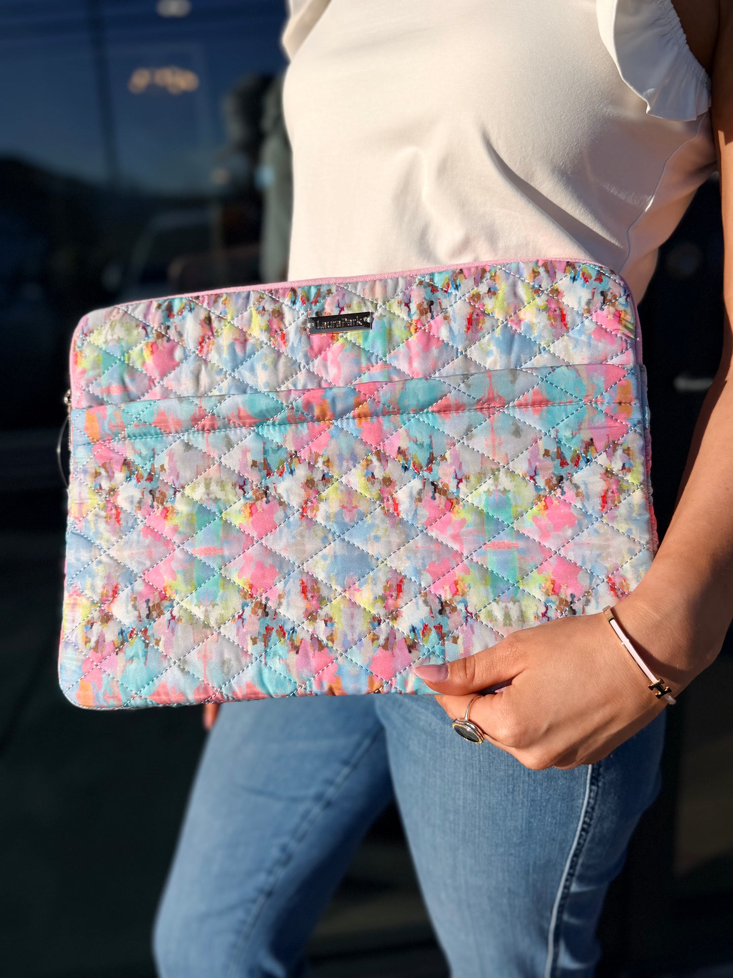 Person holding a colorful quilted clutch with a blurred background