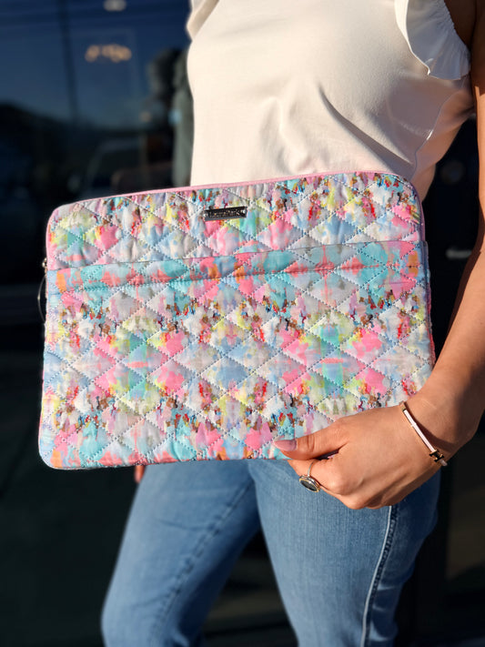 Person holding a colorful quilted clutch with a blurred background