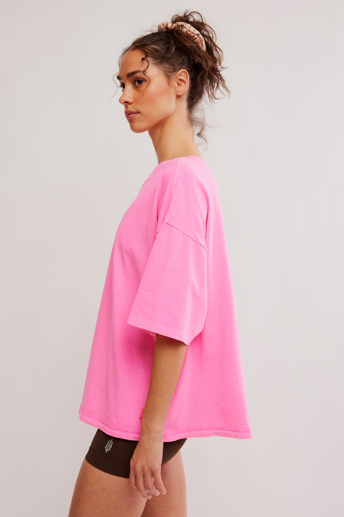 Model wearing Pink Top with brown biker shorts facing the side