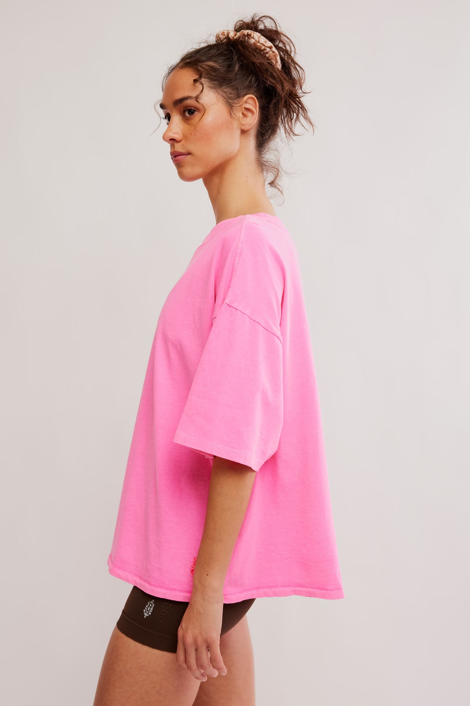 Model wearing Pink Top with brown biker shorts facing the side