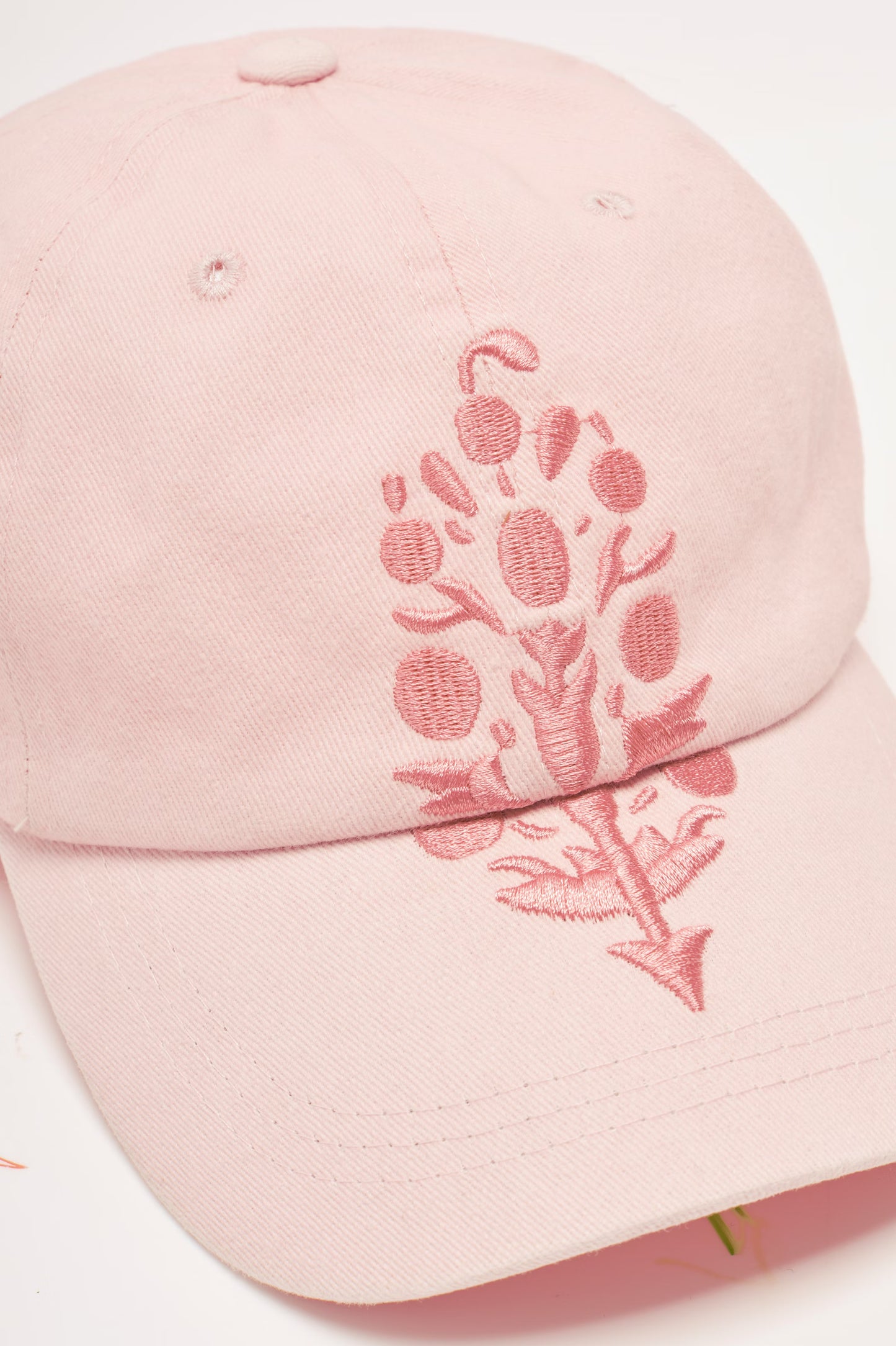 A light pink cotton baseball cap featuring a matching pink embroidered botanical design on the front panel and brim.