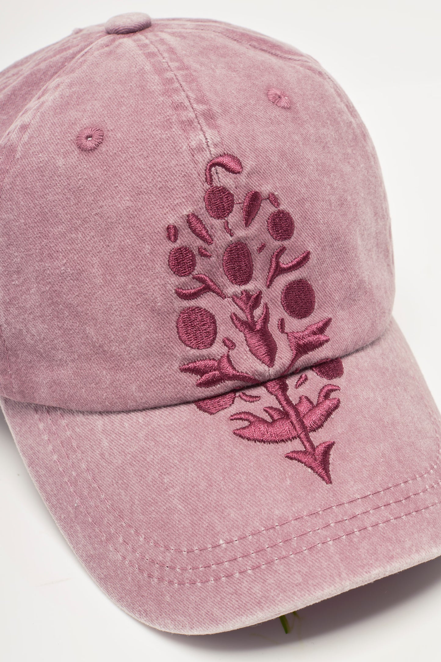 Pink baseball cap with floral embroidery on a light gray background
