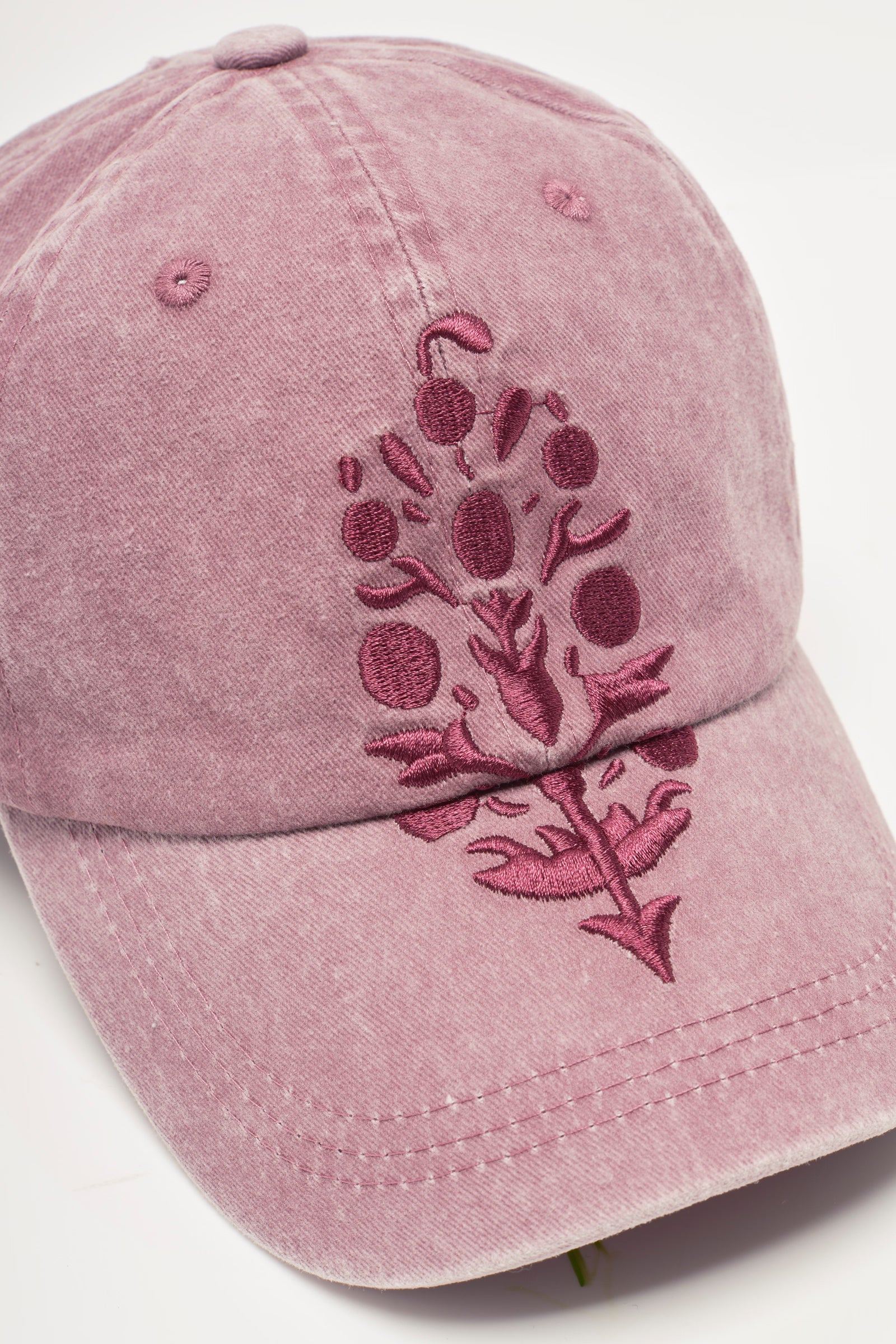 Pink baseball cap with floral embroidery on a light gray background