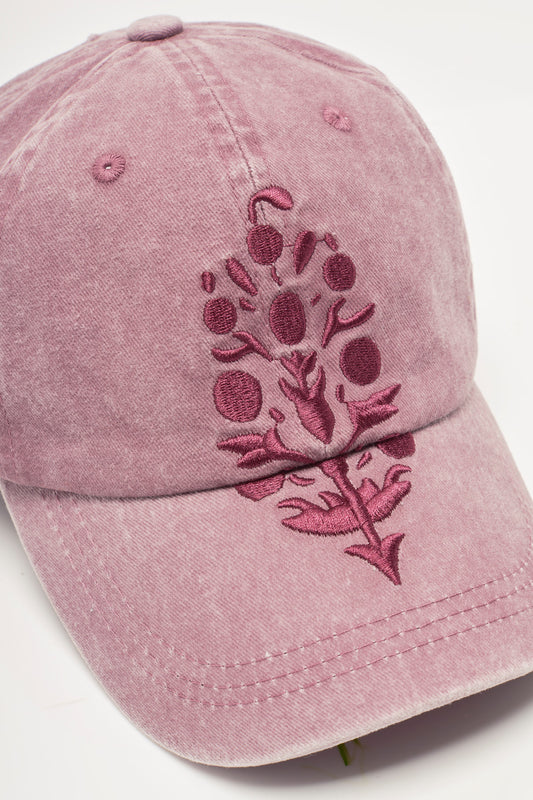 Pink baseball cap with floral embroidery on a light gray background