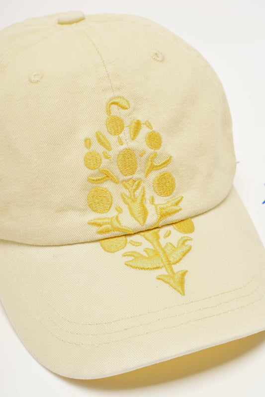 A light cream-colored cotton baseball cap featuring a yellow embroidered floral design on the front panel, set against a plain white background.