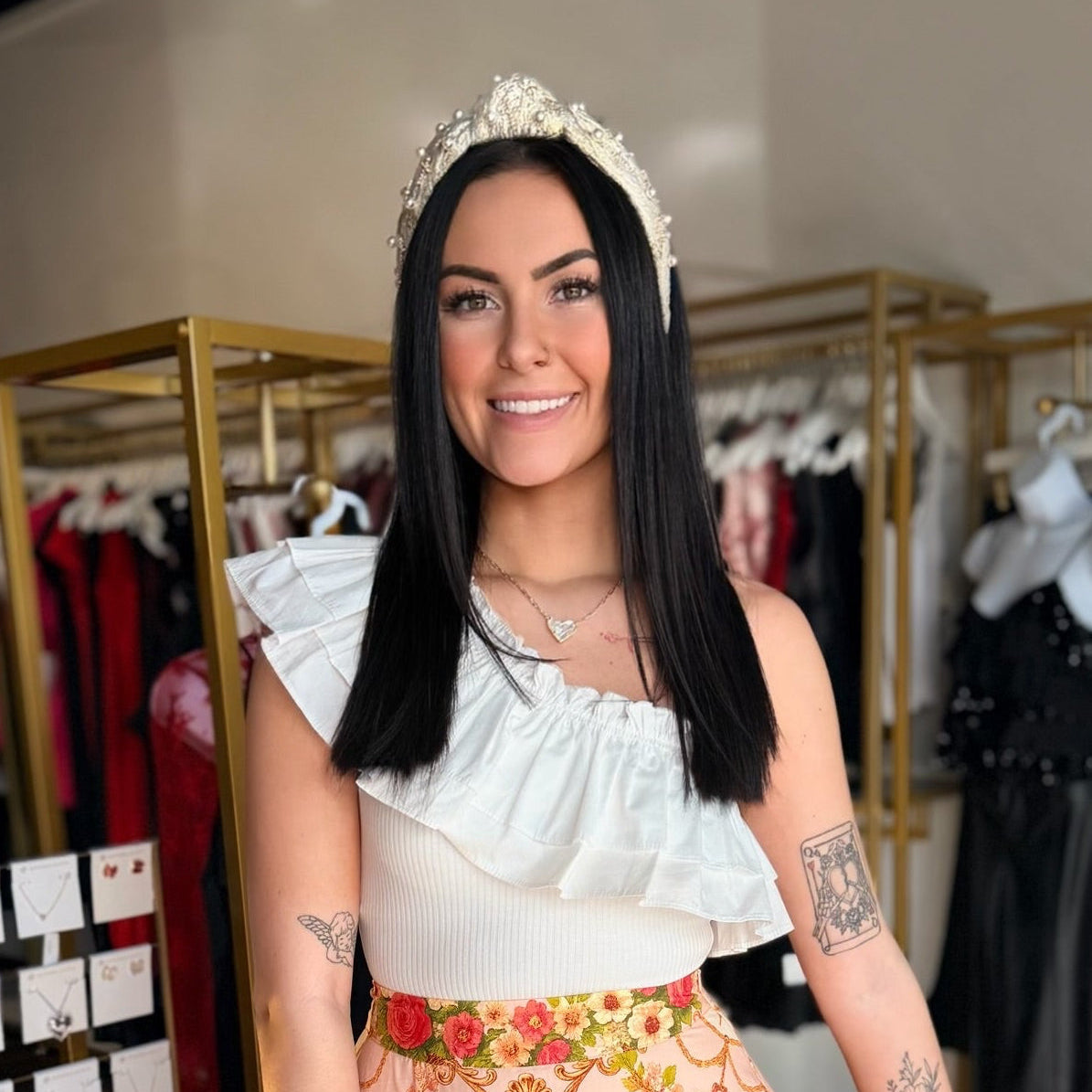 Woman in a stylish outfit with a floral skirt and white top in a clothing store.
