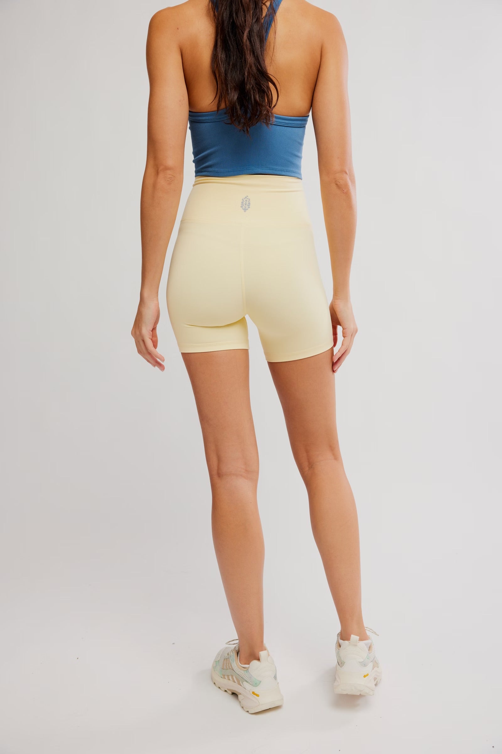 Person wearing a blue top and yellow shorts on a plain background