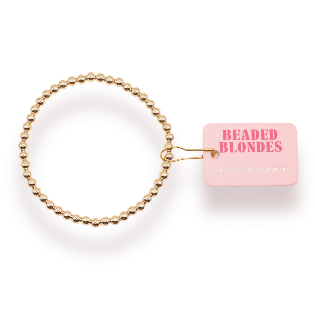 Beaded Blondes 4mm Gold Bracelet beside a pink jewelry tag.