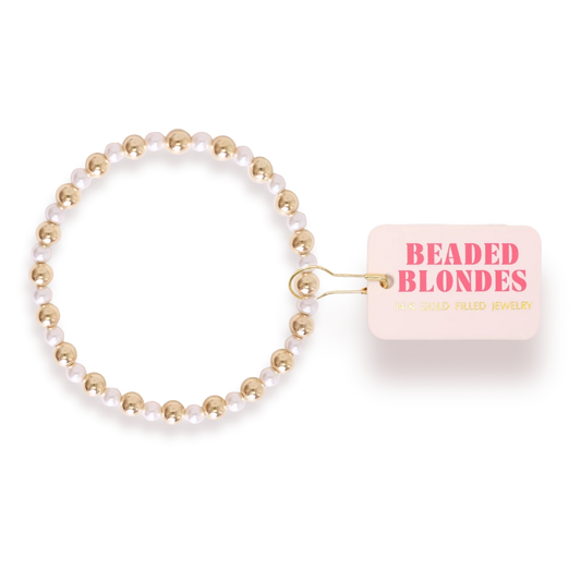 Beaded Blondes Anna Pearl Bracelet Gold shown beside its jewelry tag.