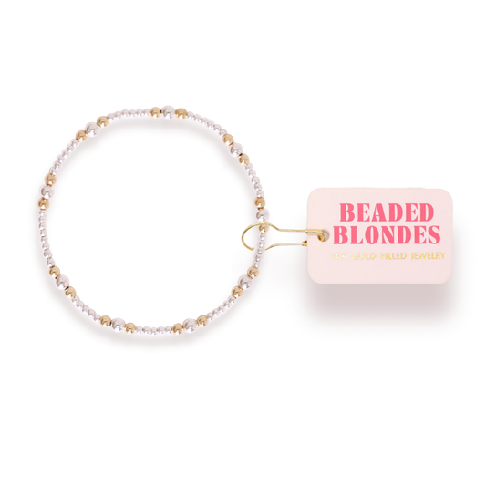 Beaded Blondes Dainty Sutton Bracelet in Silver with Gold beside a pink jewelry tag.