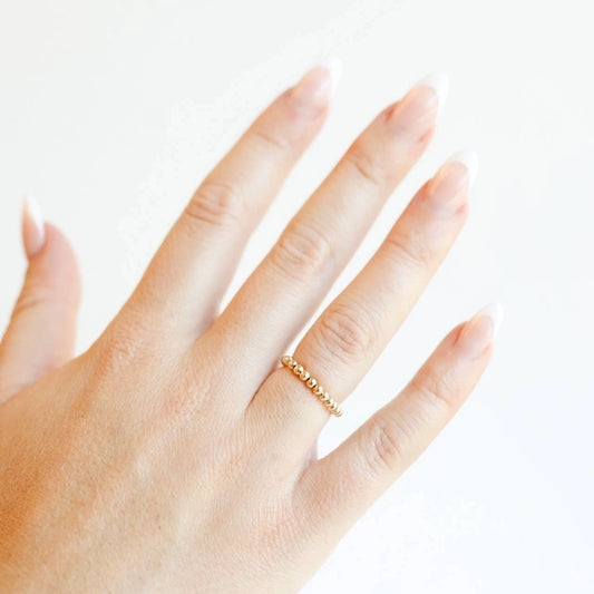 Beaded Blondes Ella Beaded Band Ring in Gold worn alone on a hand against a white background.