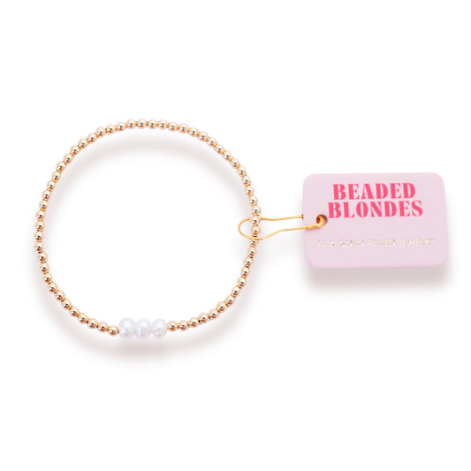 Beaded Blondes Harper Pearl Bracelet in Gold beside a pink jewelry tag.