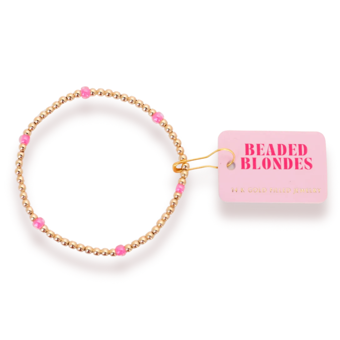 Beaded Blondes Hot Pink Poppi Bracelet with hot pink glass accents and gold beads beside a pink brand tag.