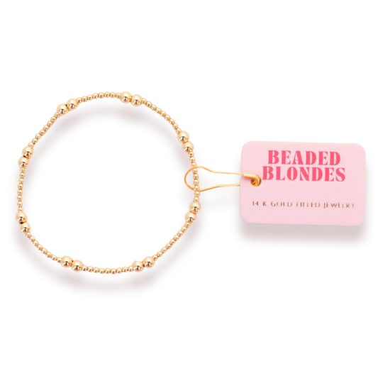 Beaded Blondes Leah Bracelet in Gold, showing its mixed bead pattern beside a pink brand tag.