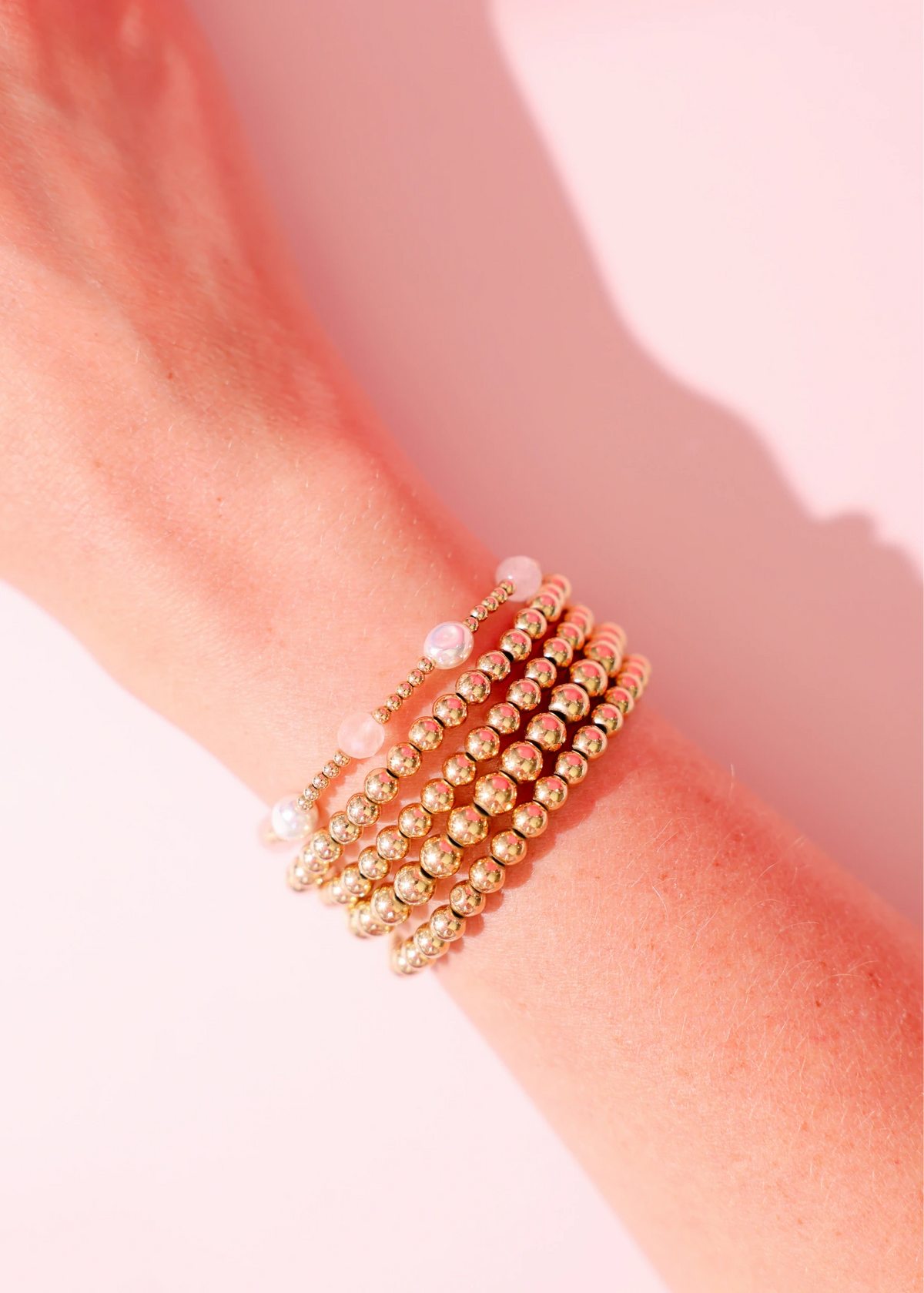 Layered pink and gold bracelets worn together on a wrist.