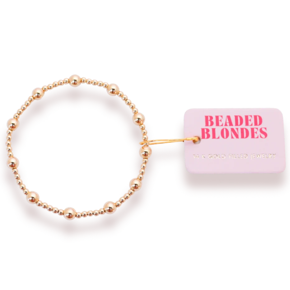Beaded Blondes Lively Bracelet in Gold beside a pink jewelry tag.