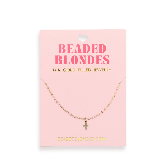 Beaded Blondes Mini Cross Charm Necklace displayed on a pink jewelry card.